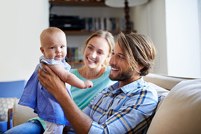 Buy stock photo Shot of a young couple playing with their baby on the sofa at home