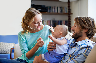 Buy stock photo Shot of a young couple playing with their baby on the sofa at home
