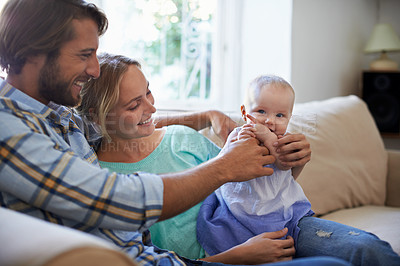 Buy stock photo Shot of a young couple playing with their baby on the sofa at home