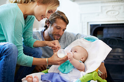 Buy stock photo Shot of a young couple feeding their baby at home