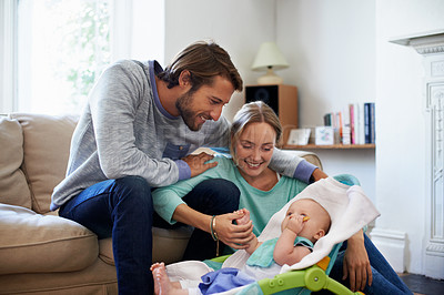 Buy stock photo Shot of a young couple playing with their baby at home