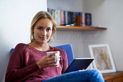 Buy stock photo Portrait of a young woman using a digital tablet and drinking a coffee while relaxing at home