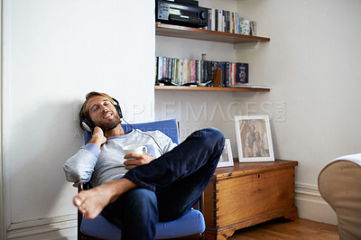 Buy stock photo Shot of a young man relaxing at home listening to music