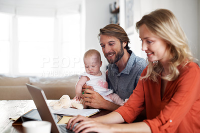 Buy stock photo Shot of a couple using a laptop while cradling their baby