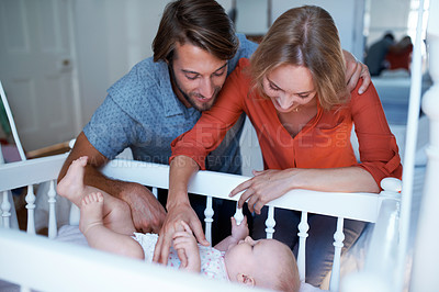 Buy stock photo Shot of a couple looking at their baby lying in a crib