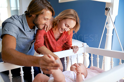 Buy stock photo Shot of a couple looking at their baby lying in a crib