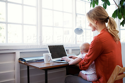 Buy stock photo Shot of a mother using a laptop with her baby sitting on her lap