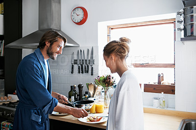Buy stock photo Shot of a young couple cooking breakfast together in the kitchen
