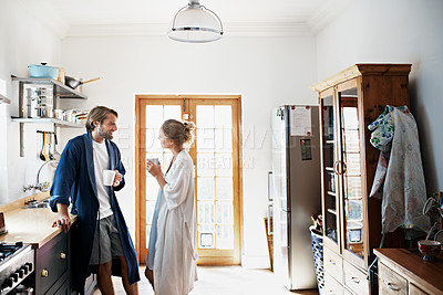 Buy stock photo Shot of a young couple drinking coffee in the kitchen in the morning