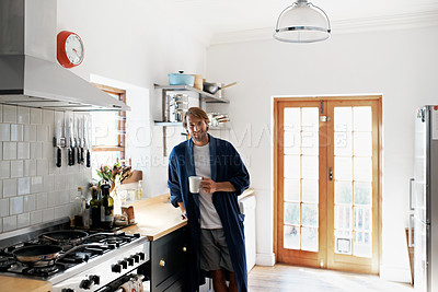 Buy stock photo Portrait of a young man drinking a coffee in the kitchen in the morning