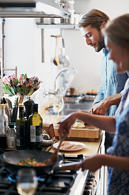 Buy stock photo Shot of a young couple cooking together in the kitchen