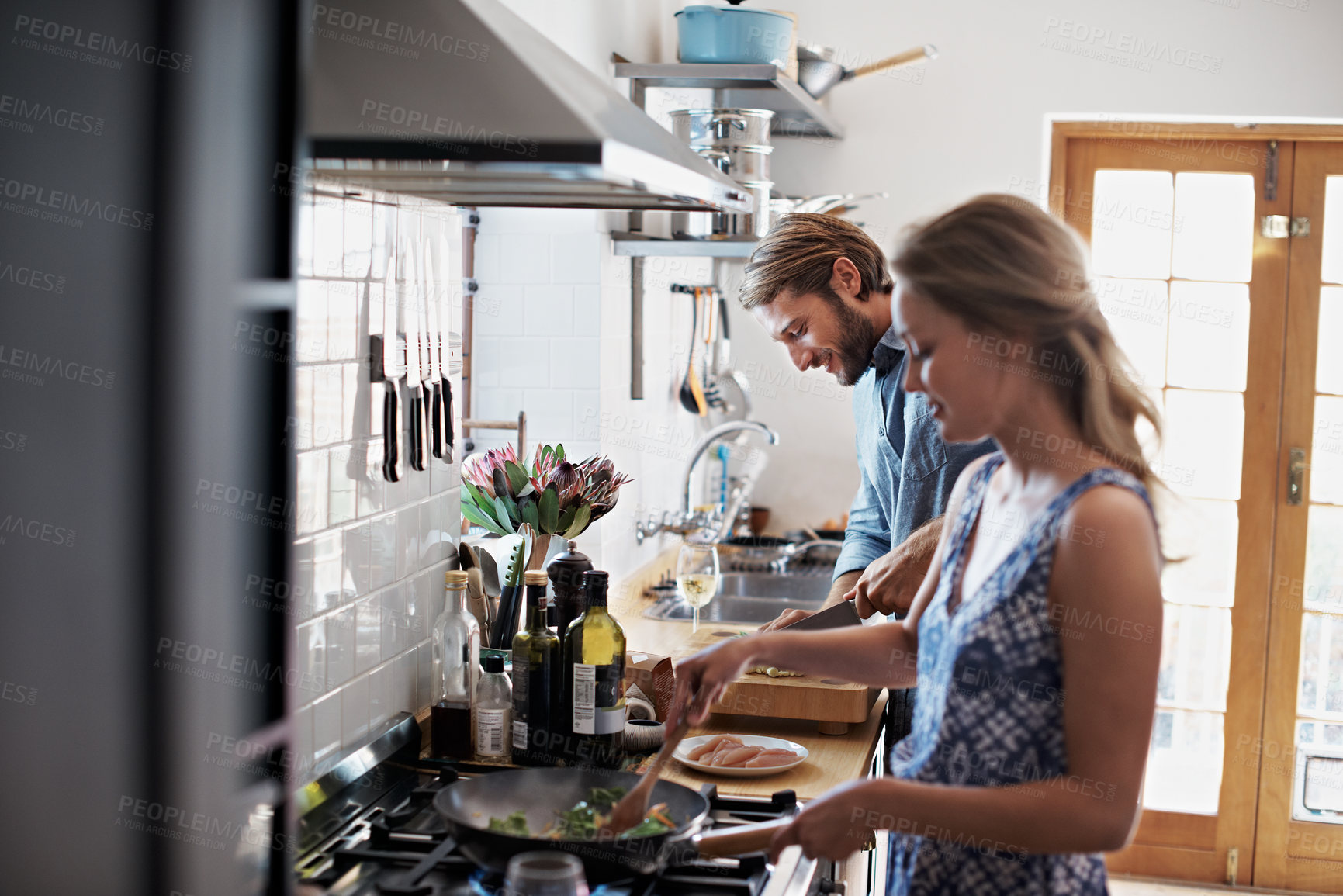 Buy stock photo Shot of a young couple cooking together in the kitchen