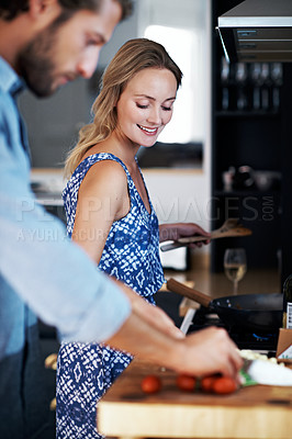 Buy stock photo Shot of a young couple cooking together in the kitchen