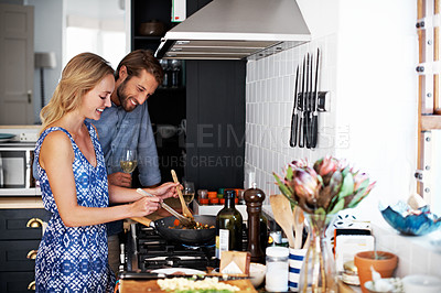 Buy stock photo Shot of a young couple cooking together in the kitchen