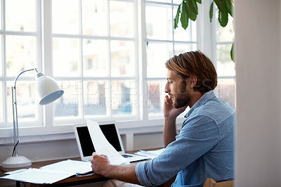 Buy stock photo Shot of a young man talking on his cellphone in his study at home