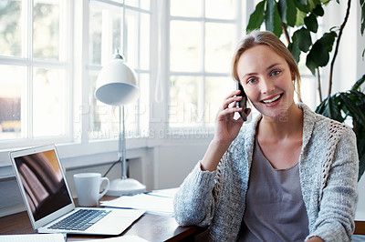 Buy stock photo Portrait of a young woman talking on the phone while working on a laptop at home