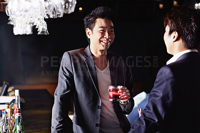 Buy stock photo Shot of a two male friends drinking and talking together in a nightclub
