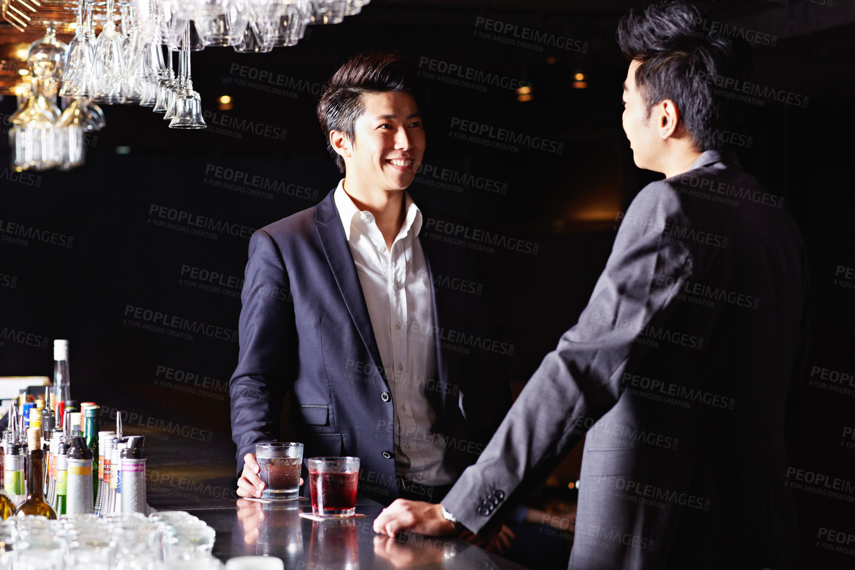 Buy stock photo Shot of a two male friends drinking and talking together in a nightclub