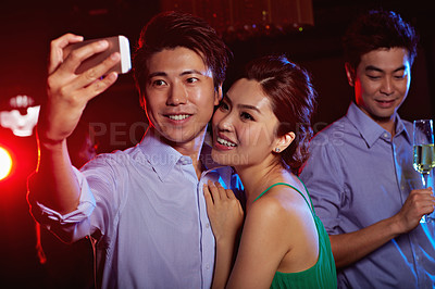 Buy stock photo Shot of an attractive young asian couple taking a selfie in a nightclub