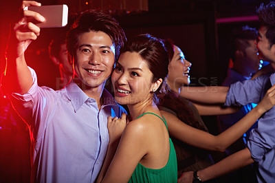 Buy stock photo Shot of an attractive young asian couple taking a selfie in a nightclub