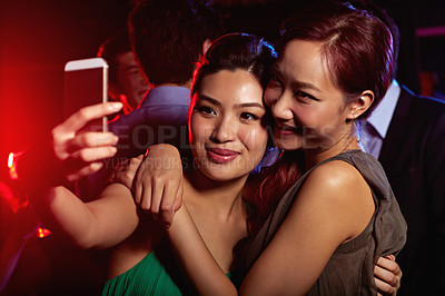 Buy stock photo Shot of a two attractive female friends taking a selfie in a nightclub