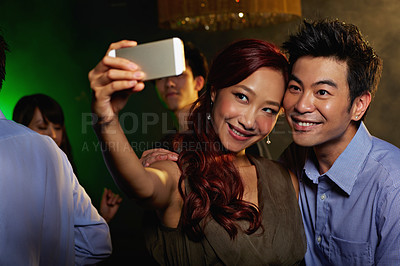 Buy stock photo Shot of an attractive young asian couple taking a selfie in a nightclub