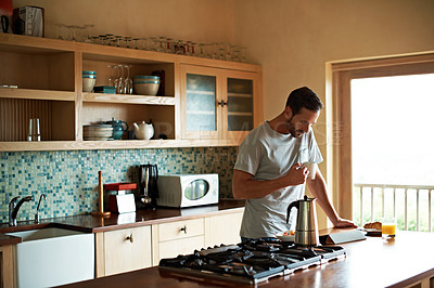 Buy stock photo Cropped shot of a handsome man eating breakfast while using a tablet