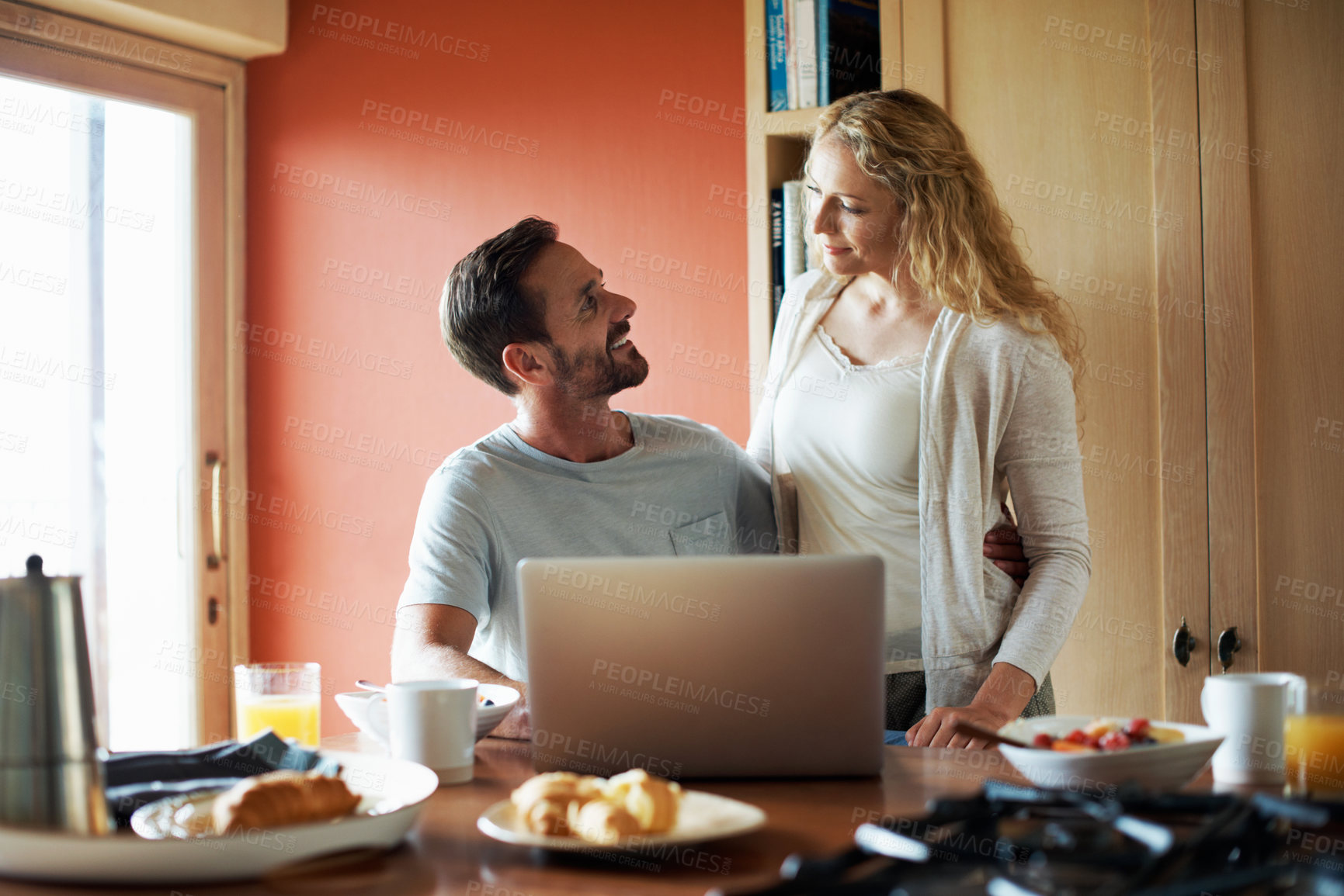 Buy stock photo Happy, breakfast and couple on laptop in kitchen for website, internet and connection in morning. Marriage, home and man with woman for bonding, talk and love on computer for news, email and research