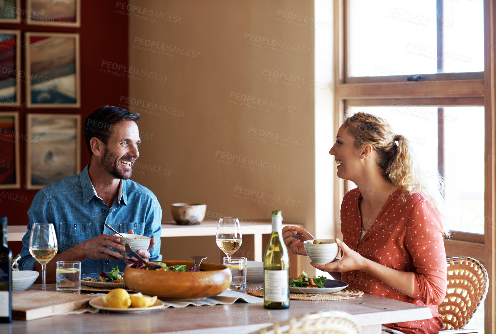 Buy stock photo Eating, couple and laugh in home for lunch date, healthy dish and funny chat with bonding. Conversation, happy mature people and joke at dining table for anniversary food, nutrition and relationship