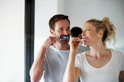 Buy stock photo Cropped shot of a couple brushing their teeth in the bathroom