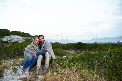 Buy stock photo Cropped shot of an affectionate couple wrapped in a blanket while sitting outdoors