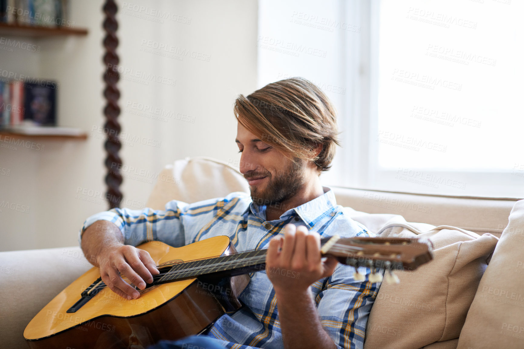 Buy stock photo Sofa, man and play guitar for music, practice song and talent performance on weekend. Home, happy person and musician with acoustic instrument for creative skill, audio and rhythm at apartment