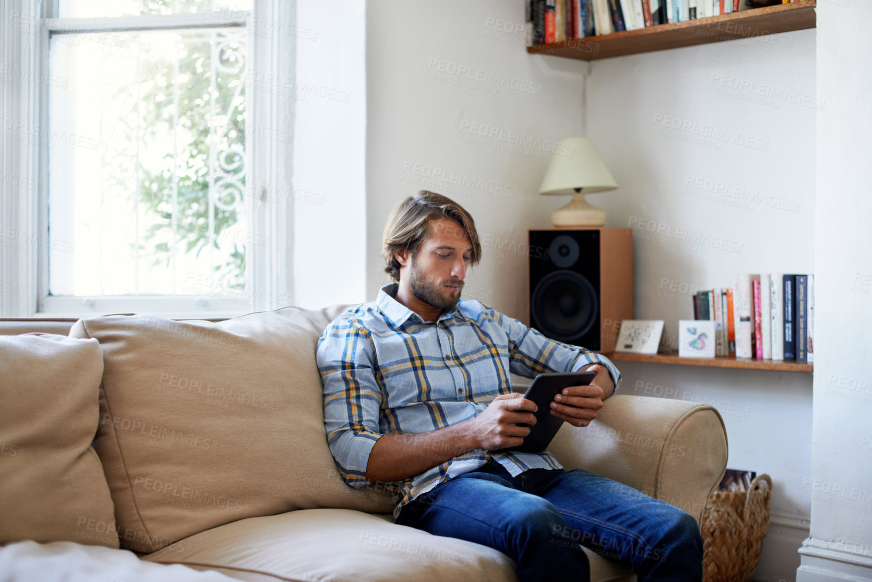 Buy stock photo Sofa, relax or man with tablet for reading ebook, internet search or blog post in living room. Technology, home and male person with digital literature, browsing online or newsletter app on weekend