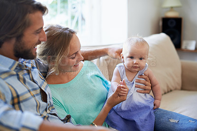 Buy stock photo Shot of a young couple sitting on the sofa at home with their baby