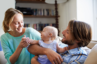 Buy stock photo Shot of a young couple playing with their baby at home
