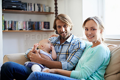 Buy stock photo Portrait of a young couple sitting on the sofa with their baby
