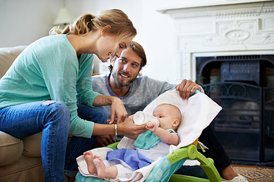 Buy stock photo Shot of a young couple feeding their baby at home