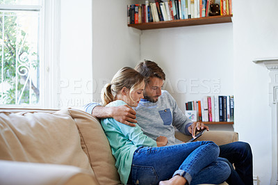 Buy stock photo Shot of a young couple using a digital tablet while relaxing on a sofa at home