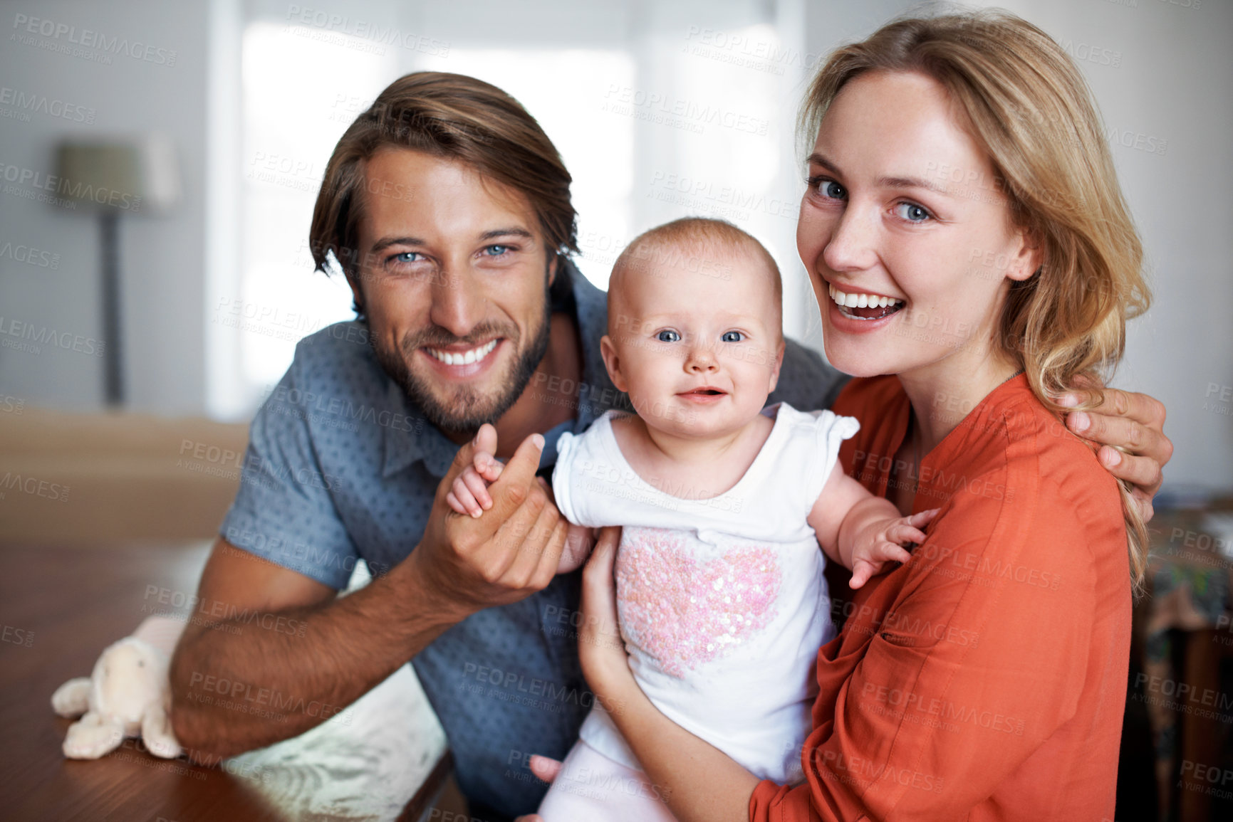 Buy stock photo Portrait of a smiling young dad with his wife and their baby girl at home