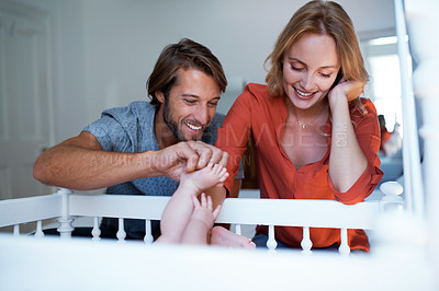 Buy stock photo Shot of a couple looking at their baby lying in a crib