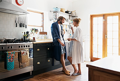 Buy stock photo Shot of a young couple standing together drinking coffee in the kitchen