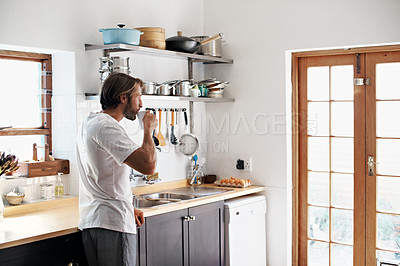 Buy stock photo Shot of a young man drinking  coffee in the kitchen in the morning