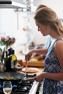 Buy stock photo Shot of a young couple cooking together in the kitchen