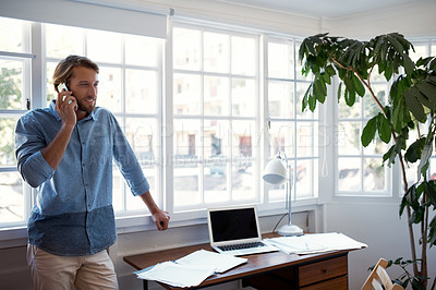 Buy stock photo Shot of a young man talking on his cellphone at home