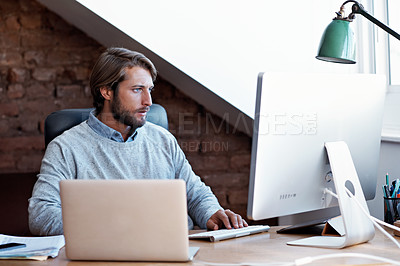 Buy stock photo Shot of a young man working on his computer at home