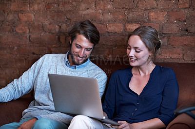 Buy stock photo Shot of a young couple using a digital tablet and laptop while relaxing at home