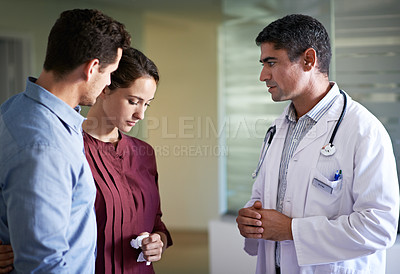 Buy stock photo Shot of a doctor delivering news to a couple in a hospital waiting room