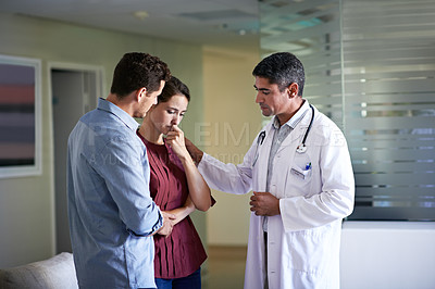 Buy stock photo Shot of a doctor delivering news to a couple in a hospital waiting room
