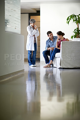 Buy stock photo Shot of a doctor delivering news to a couple in a hospital waiting room
