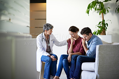 Buy stock photo Shot of a compassionate doctor delivering news to a couple in a hospital waiting room